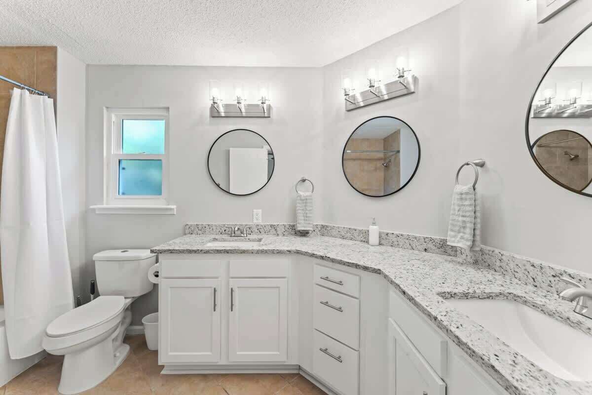 Een badkamer met toilet, wastafel, badkamermeubel en spiegels.