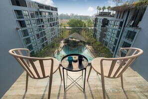 A balcony with two chairs and a small table, overlooking a swimming pool and a sports field. - Citygate Kamala Residence B705 (Kamala)