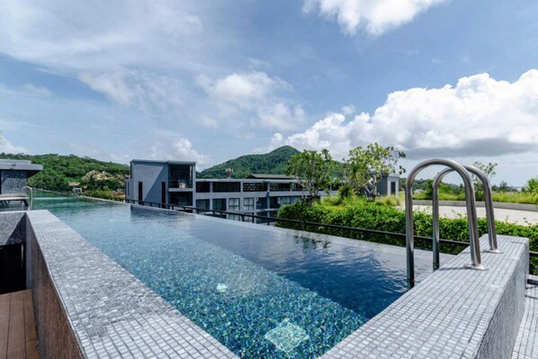 A modern hotel with a swimming pool, a mountain view, and a contemporary building design. - Citygate Kamala Residence B705 (Kamala)