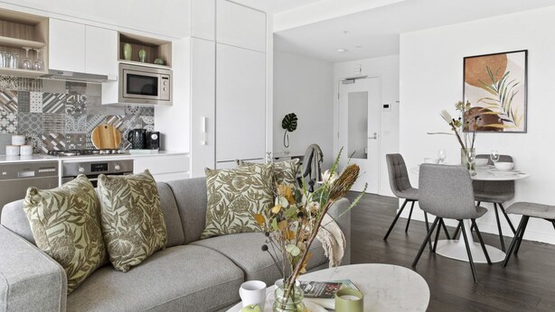 Un espacio habitable moderno con cocina, comedor y sofá con almohadones decorativos.