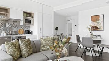 A modern living space with a kitchen, dining area, and a sofa with decorative pillows.