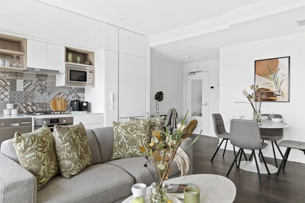 Un espacio habitable moderno con cocina, comedor y sofá con almohadones decorativos.