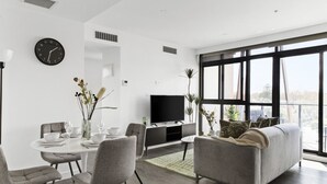 Una sala moderna con comedor, televisor de pantalla plana y ventanas amplias.