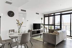 Una sala moderna con comedor, televisor de pantalla plana y ventanas amplias.