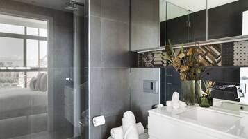 A modern bathroom with a glass shower enclosure, a white sink, and a large mirror.