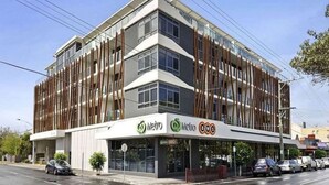 Un edificio moderno con el letrero Metro BWS, que presenta una estructura de varios pisos con amplias ventanas y techo plano.