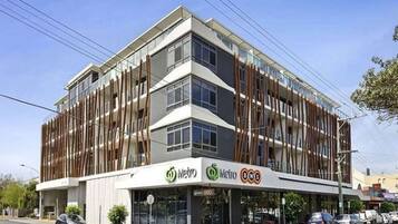 A modern building with a Metro BWS sign, featuring a multi-story structure with large windows and a flat roof.
