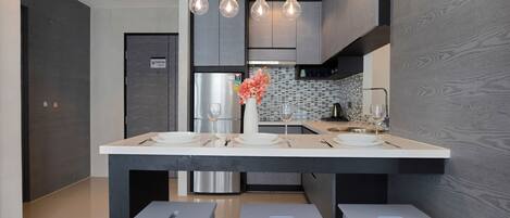 Uma cozinha moderna com ilha central, eletrodomésticos de aço inoxidável e iluminação pendente.