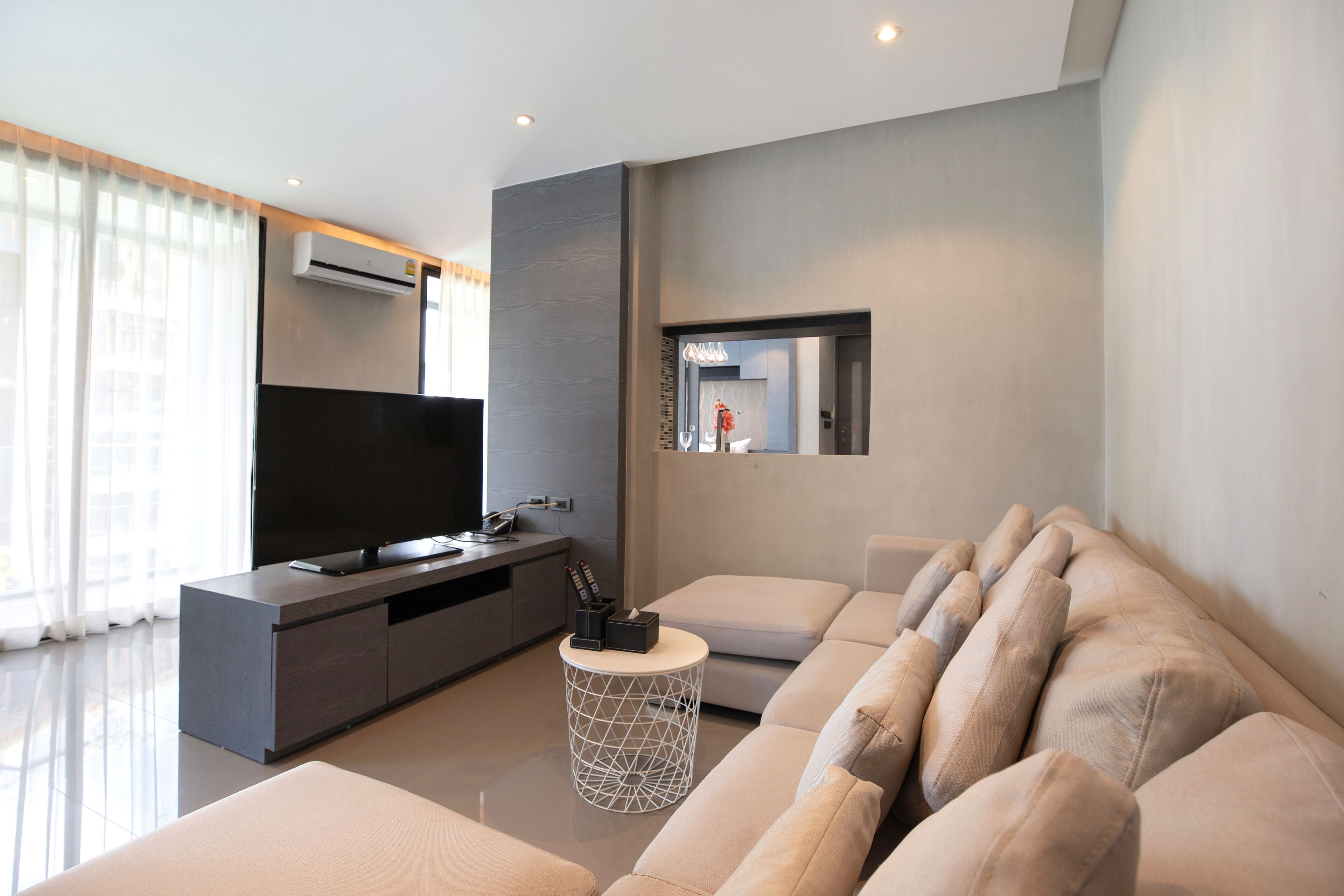 A modern living room with a large flat-screen TV, a sofa, a coffee table, and a small side table.