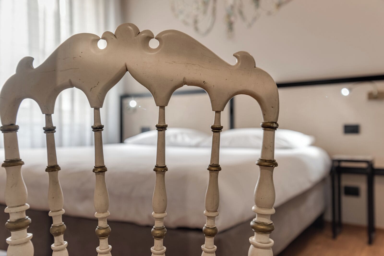 Un dormitorio con cama, mesita de noche y silla con cabecero decorativo.
