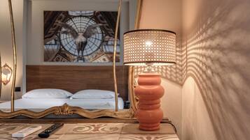 A hotel room with a bed, a decorative lamp, a remote control, and a wall painting.