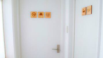A white door with three signs: "NO SMOKING," "GUEST ROOM," and "NO FOOD NO DRINK."