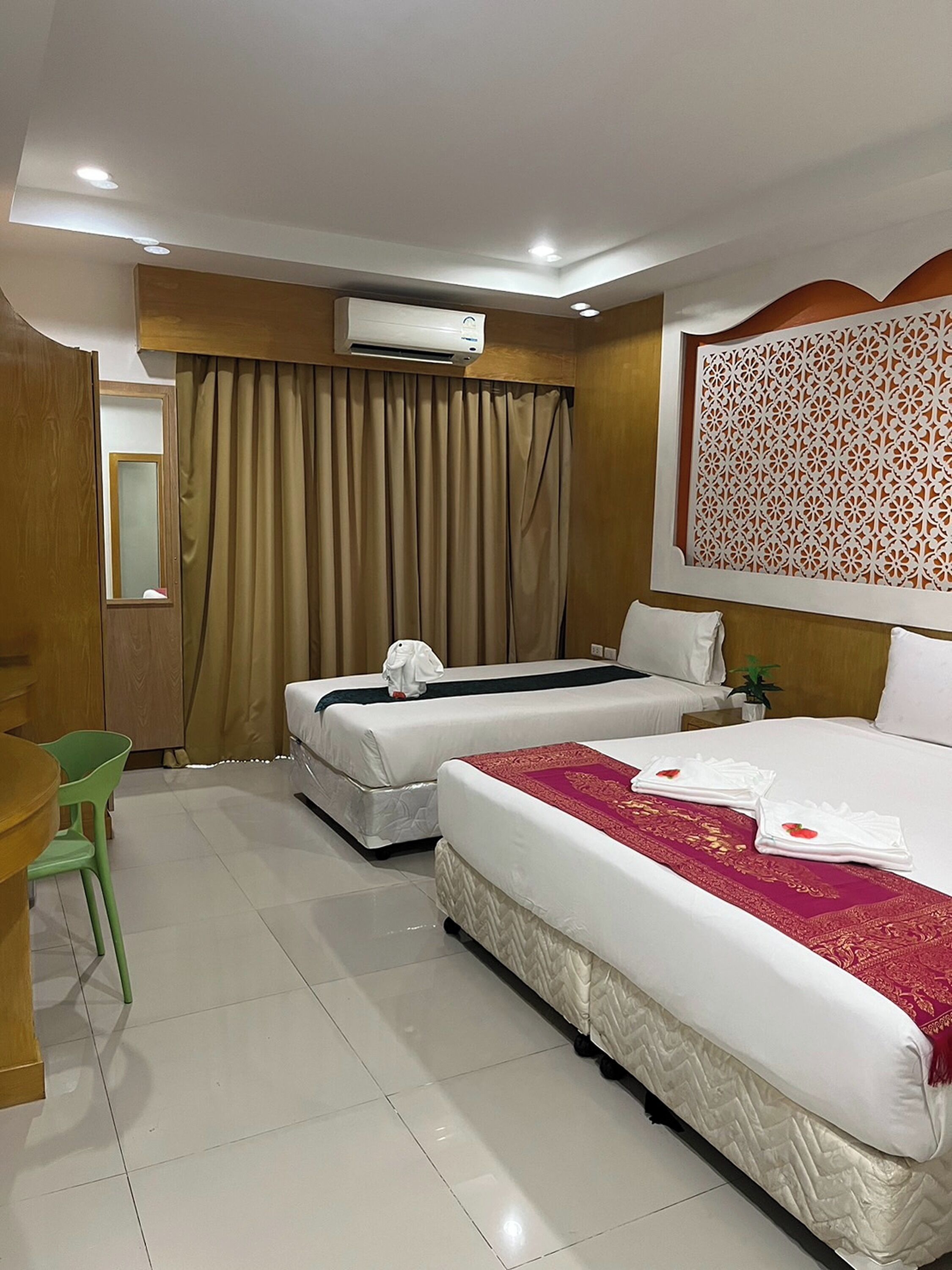 Habitación de hotel con dos camas, un escritorio, una silla y un equipo de aire acondicionado.