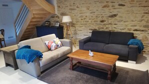 A living room with two sofas, a wooden coffee table, a lamp, and a stone wall.
