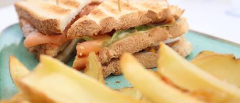 Un sándwich con palillos de dientes, lechuga y tomate, sobre un plato con papas a la francesa.