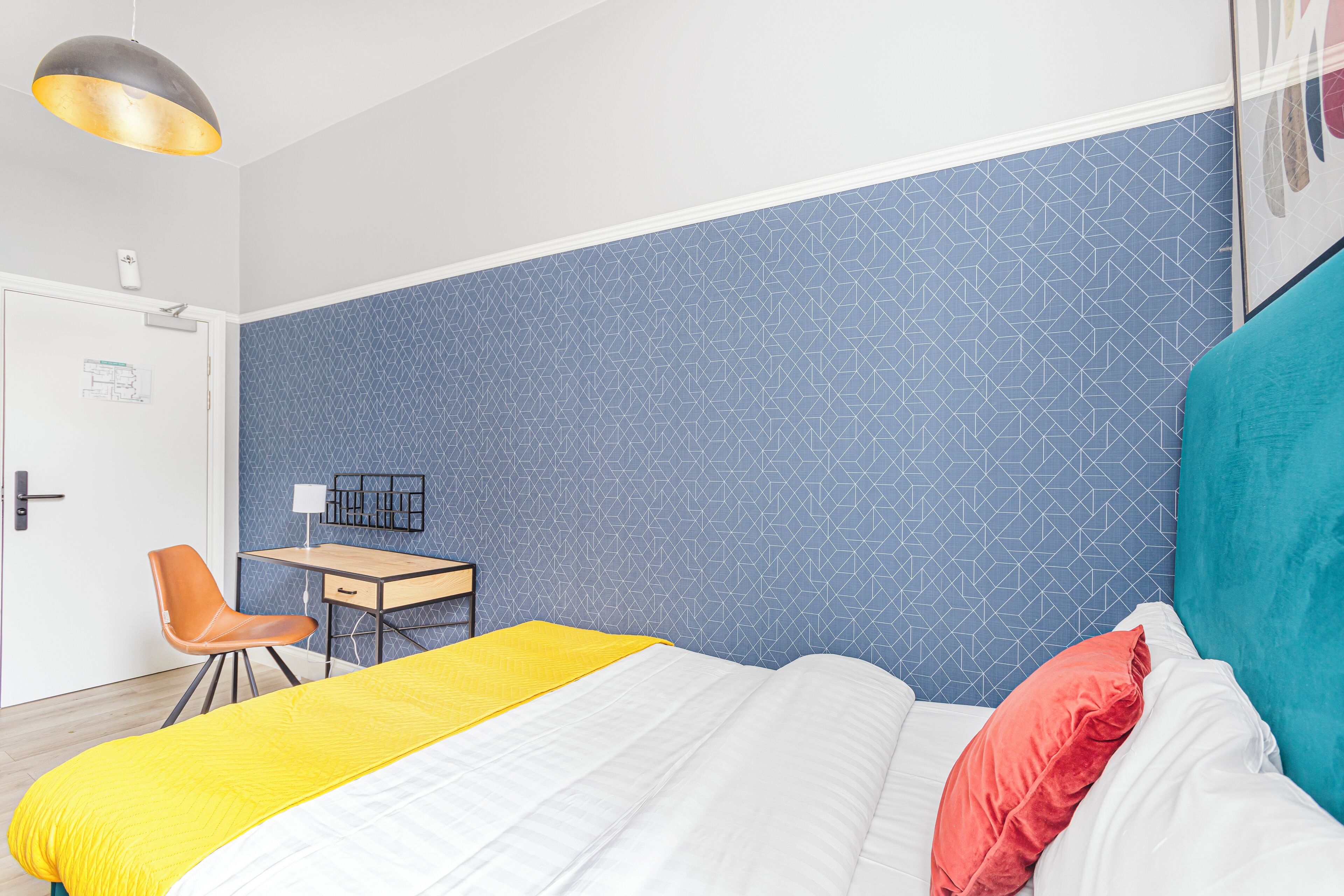 Een slaapkamer met een bed, een bureau en een stoel.