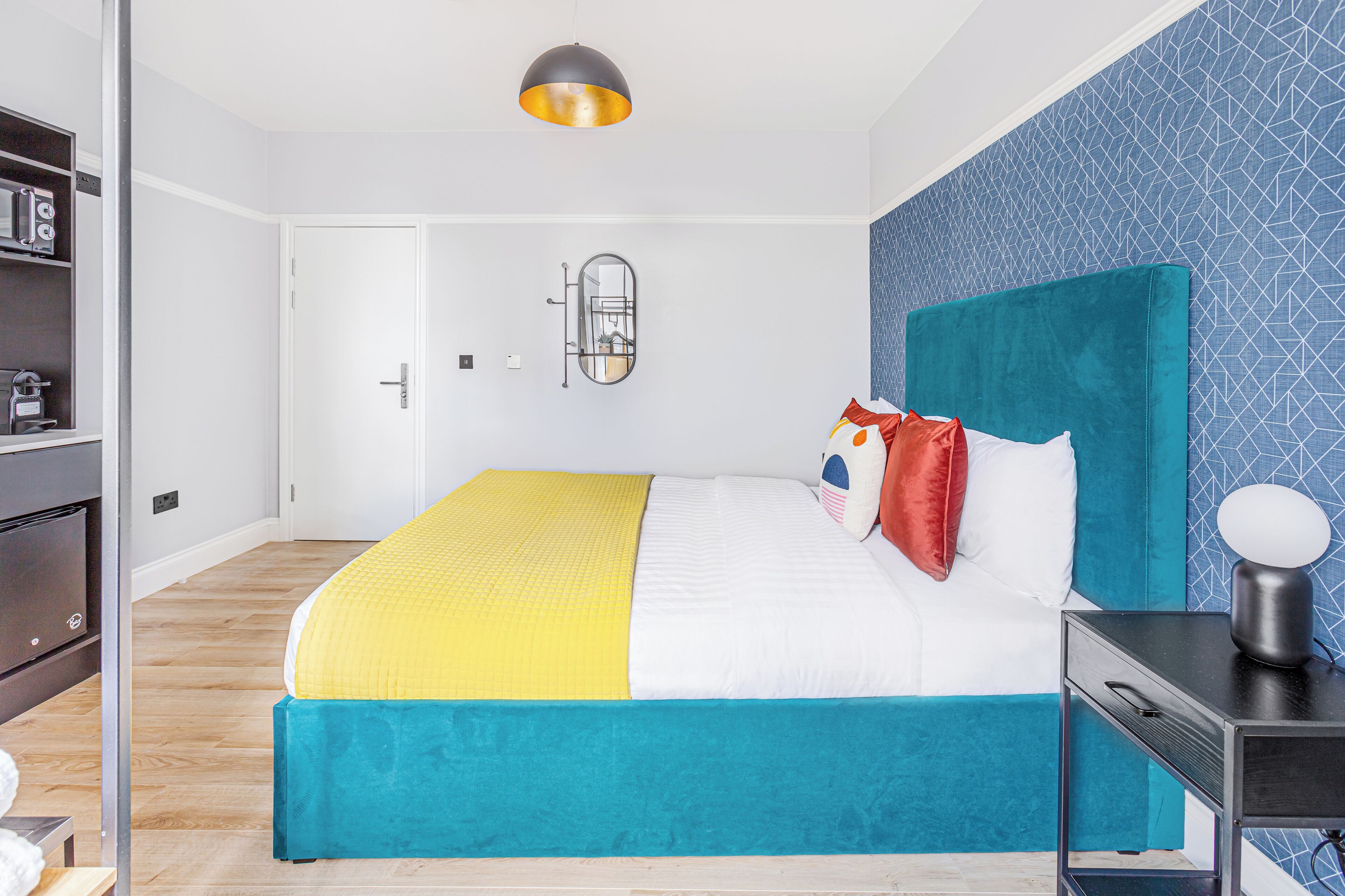 Une chambre à coucher avec un lit, une table de chevet avec une lampe, une armoire et une porte.
