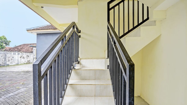 Una escalera con barandillas negras y suelo de baldosas que conduce a una plataforma.