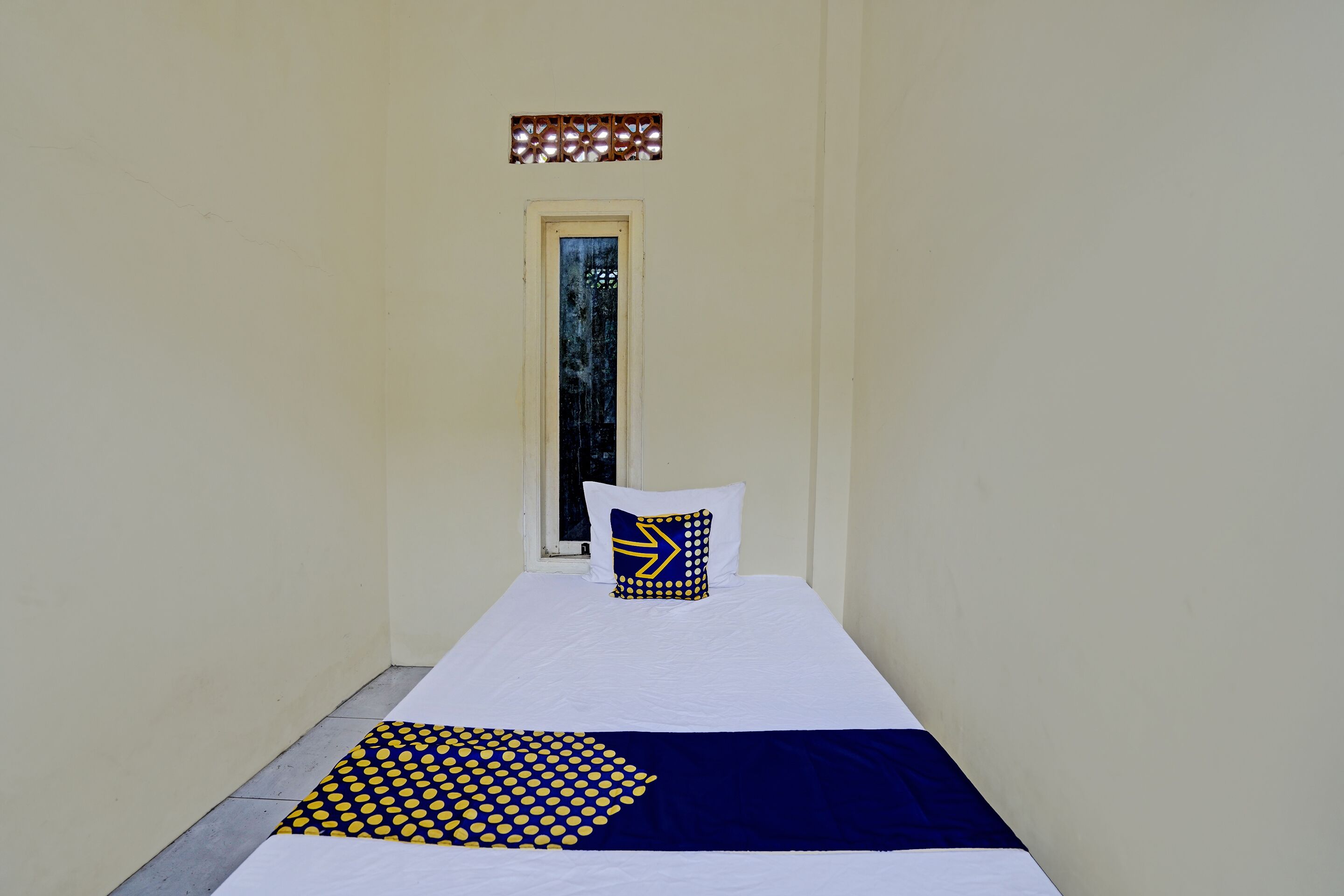 A narrow room with a bed, a window, and a door.