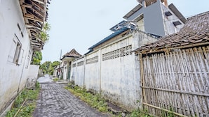 Una estrecha calle adoquinada flanqueada por edificios con paredes blancas y vallas de madera.