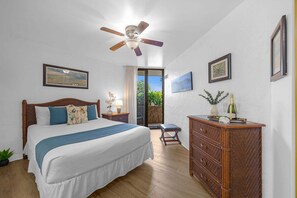 Quarto com cama, ventilador de teto, cômoda e televisão na parede.