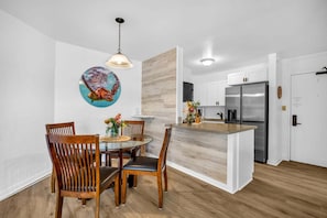 Uma cozinha moderna com uma ilha central, cadeiras de madeira, uma mesa de jantar e um lustre.