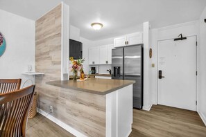 A modern kitchen with white cabinets, a stainless steel refrigerator, and a wooden island.