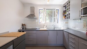 Een moderne keuken met grijze kastjes, een roestvrijstalen spoelbak en een ingebouwde magnetron.