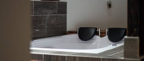 Un bagno con una vasca, due sedie nere e un armadietto in legno.