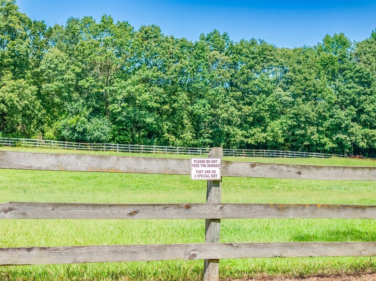 A wooden fence with a sign that reads 'PLEASE DO NOT FEED THE HORSES THEY ARE ON A SPECIAL DIET.'