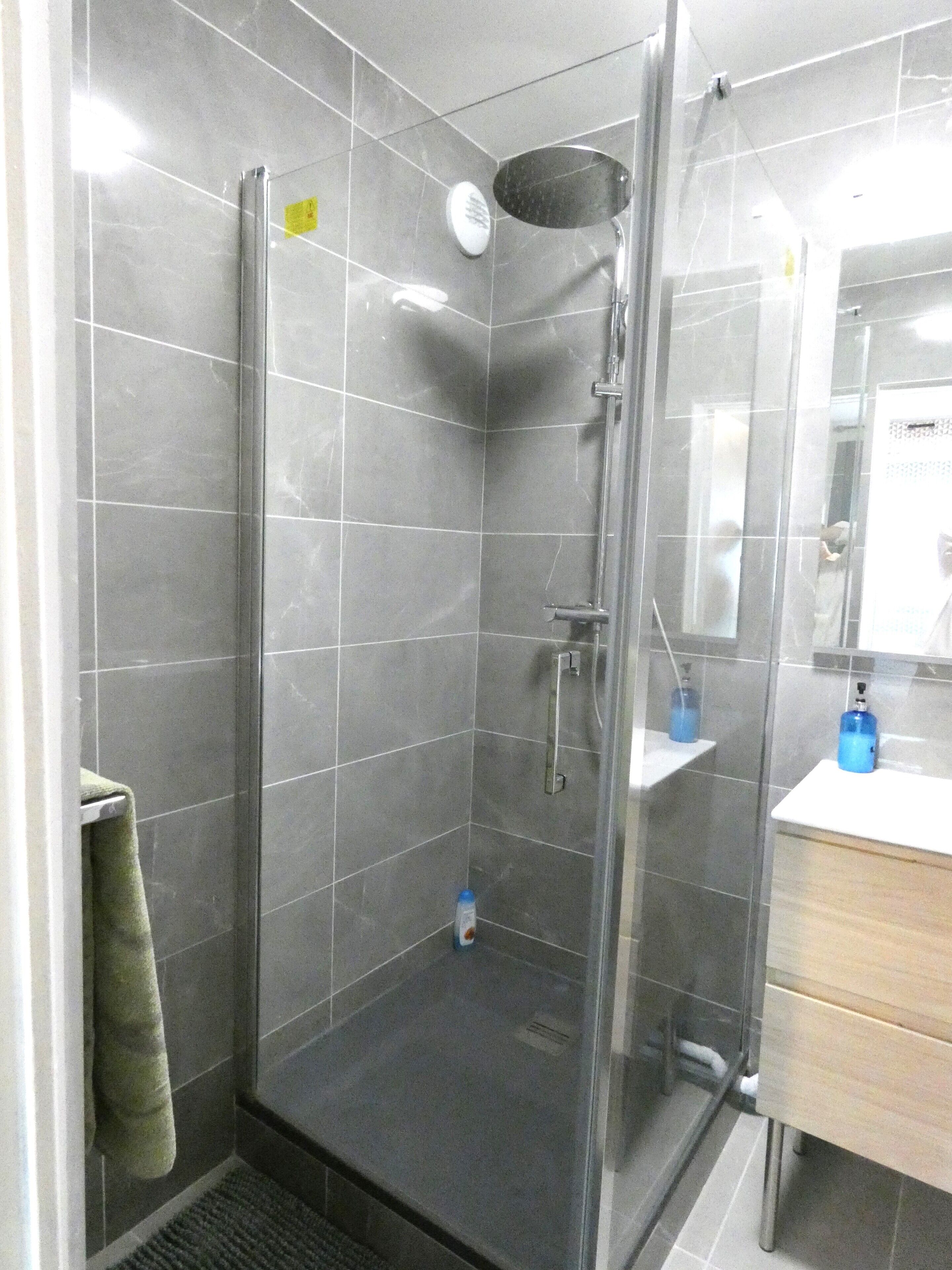 Une salle de bain moderne avec une douche à parois de verre, un lavabo avec un miroir et un porte-serviettes.