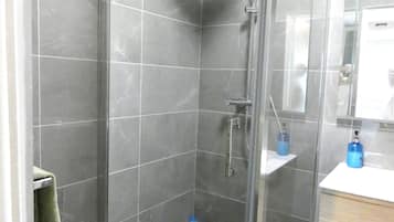 Une salle de bain moderne avec une douche à parois de verre, un lavabo avec un miroir et un porte-serviettes.
