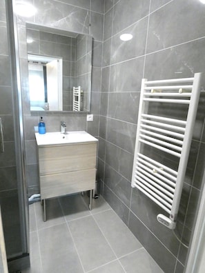 A bathroom with a white sink, a mirror, and a towel rack.