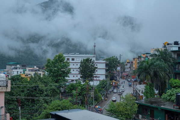 A city street with buildings, power lines, and a mountain in the background. - Orchid Hotel and Hostel (Narendranagar)