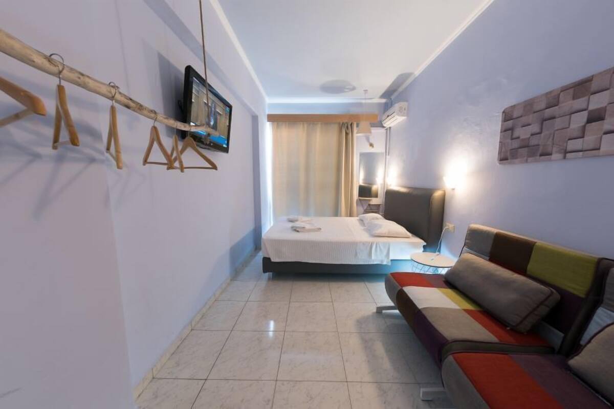 Hotellihuone, jossa on sänky, sohva, televisio ja seinälle asennettu televisio.