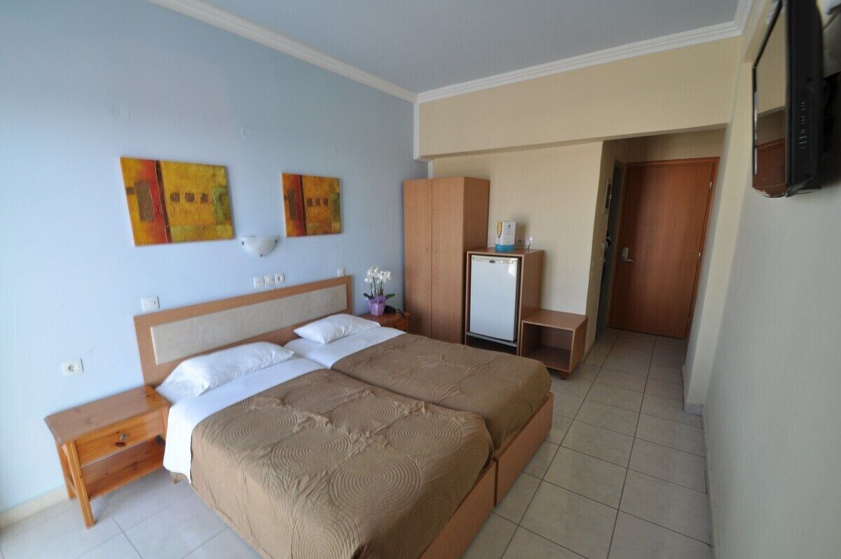 Una habitación de hotel con una cama doble, un escritorio pequeño, un televisor y un armario.