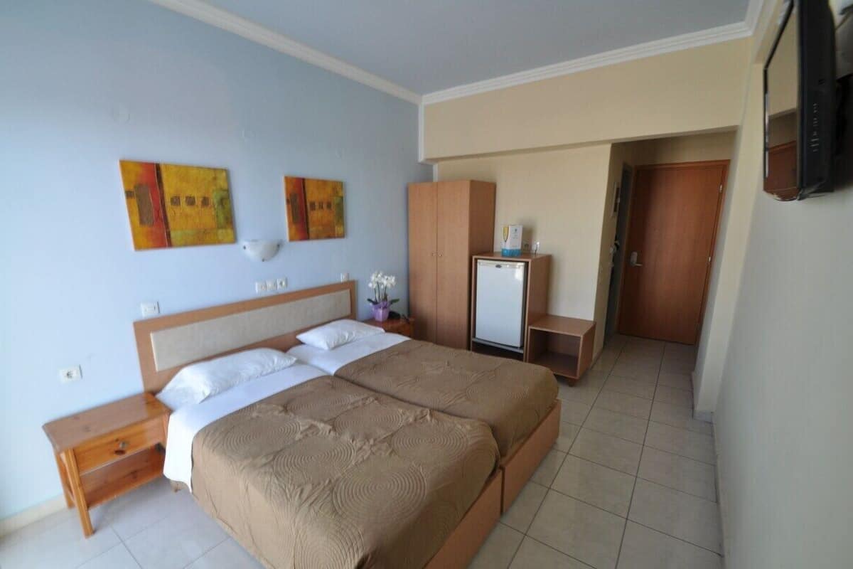 Ett hotellrum med en dubbelsäng, ett litet skrivbord, en tv och en garderob.