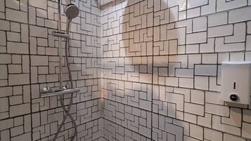 Une douche au design moderne, avec un motif géométrique sur les carreaux des murs et une étagère en bois au-dessus de la douche.