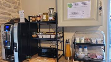 Montaje de un bufé de desayuno con una máquina de café, frascos de conservas y una variedad de alimentos a la vista.