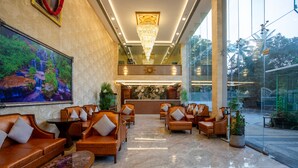 A lobby with leather sofas, a marble floor, a large chandelier, and a painting of a waterfall. - The Avenue Grand (Calangute)