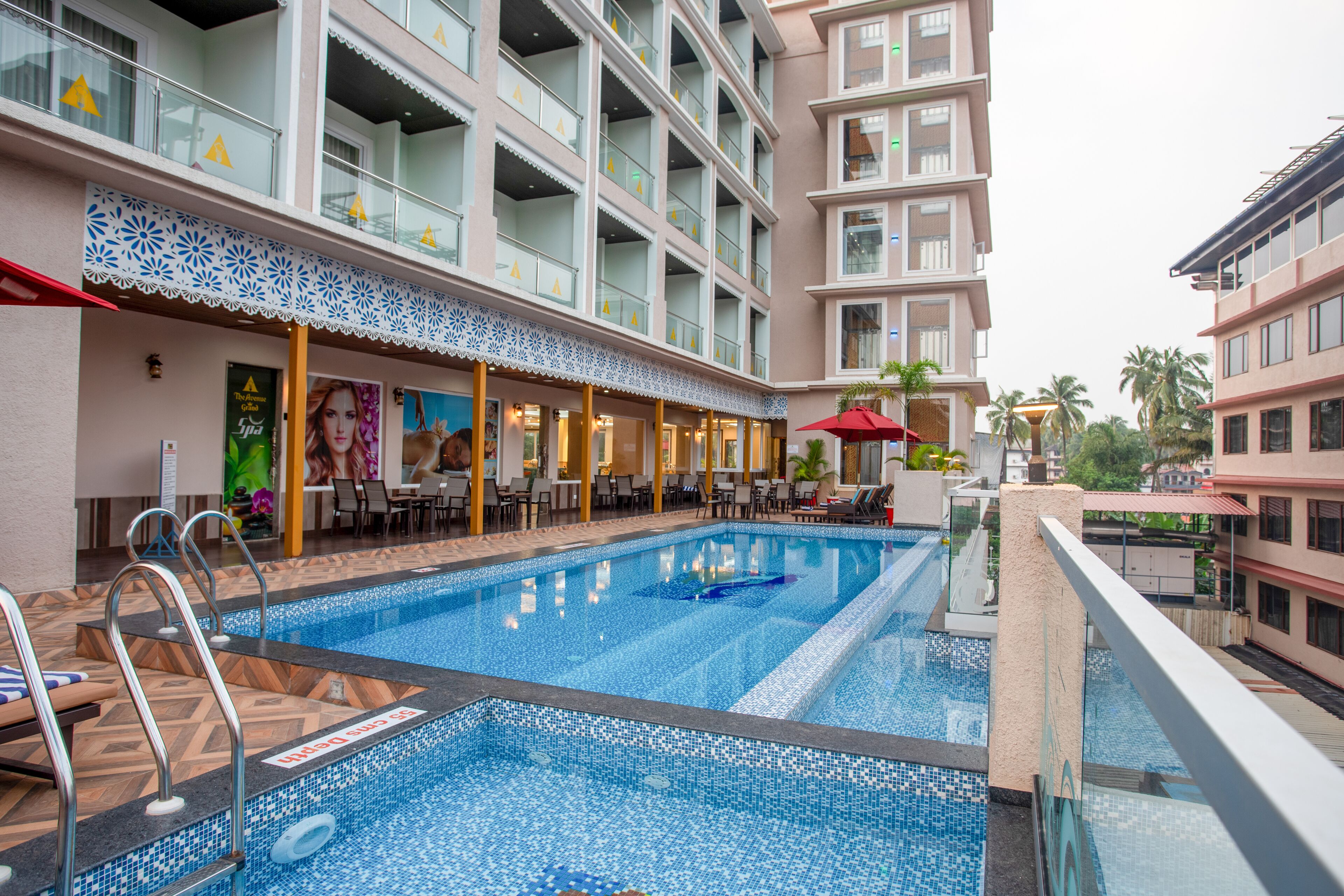 A hotel with a swimming pool, outdoor seating, and multiple balconies.