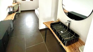 Une pièce moderne et bien éclairée, avec un bureau en bois, un miroir rond et un plateau noir posé sur une table en bois.