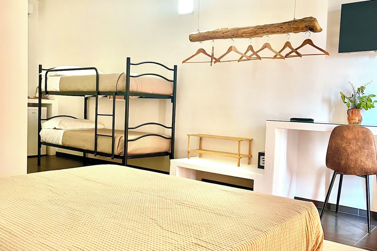 A hotel room with bunk beds, a desk, a chair, and a television.