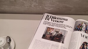 A magazine open on a table with a plate of macarons and a spoon. - il sogno di afrodite b and b luxury (Rome)