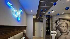 A modern bedroom with a bed, a neon chemical structure on the wall, and a classical bust sculpture. - il sogno di afrodite b and b luxury (Rome)