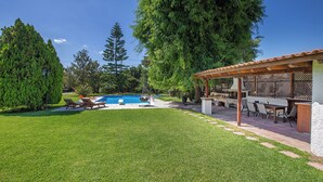 A backyard with a swimming pool, a pergola, and a patio area with outdoor furniture.