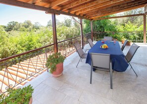An outdoor patio with a table set for four, surrounded by chairs, a potted plant, and a view of lush greenery. - Private villa w/ large pool, walking distance from beach, near Athens (Ag. Panteleimon)