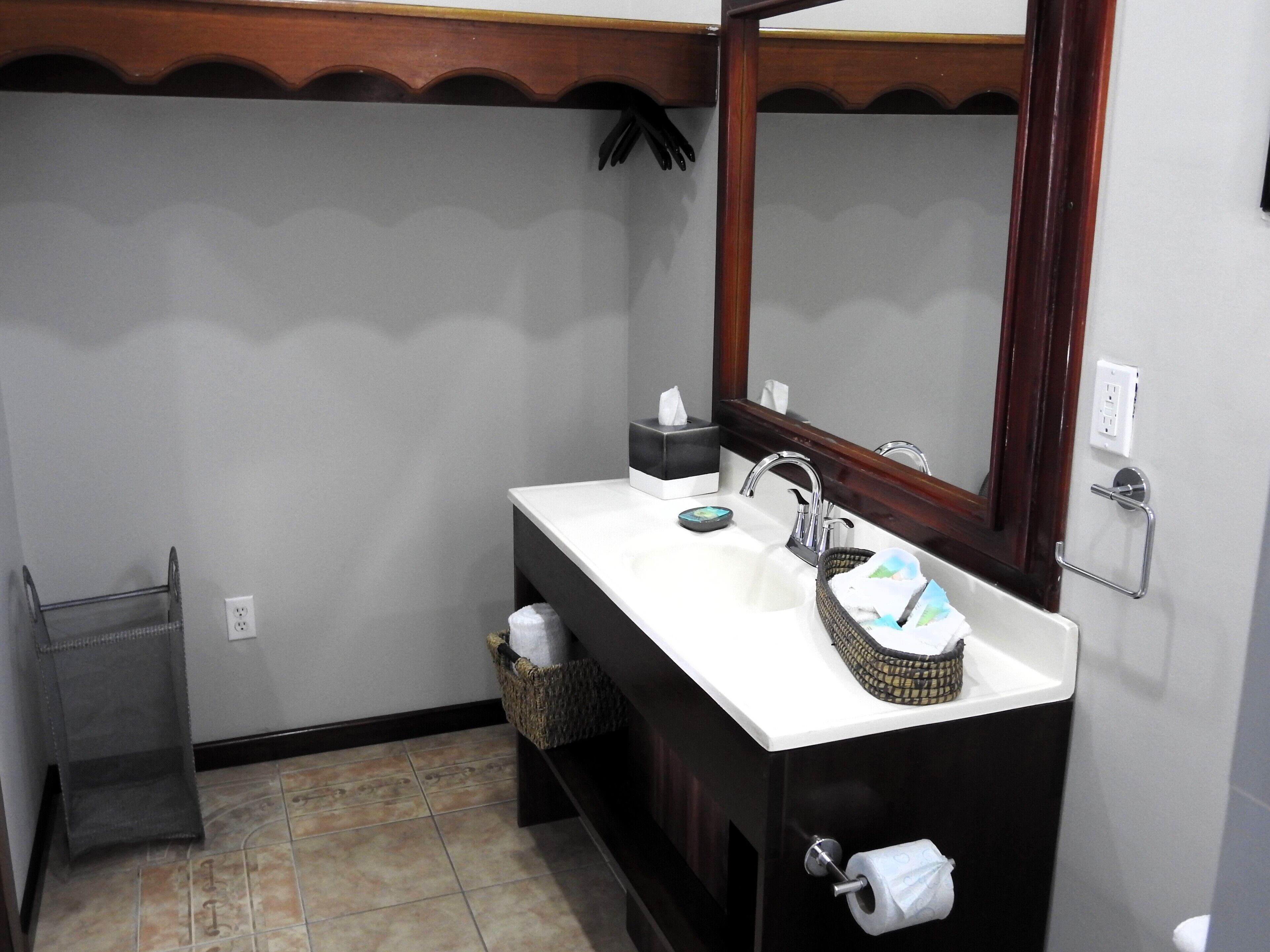 A bathroom with a white sink, dark wooden vanity, a mirror, and a towel rack.