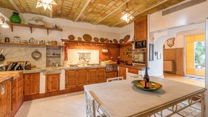 A spacious kitchen with wooden cabinets, a marble countertop, and a large island.