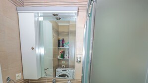 Une salle de bain avec un lavabo, un miroir et une douche.
